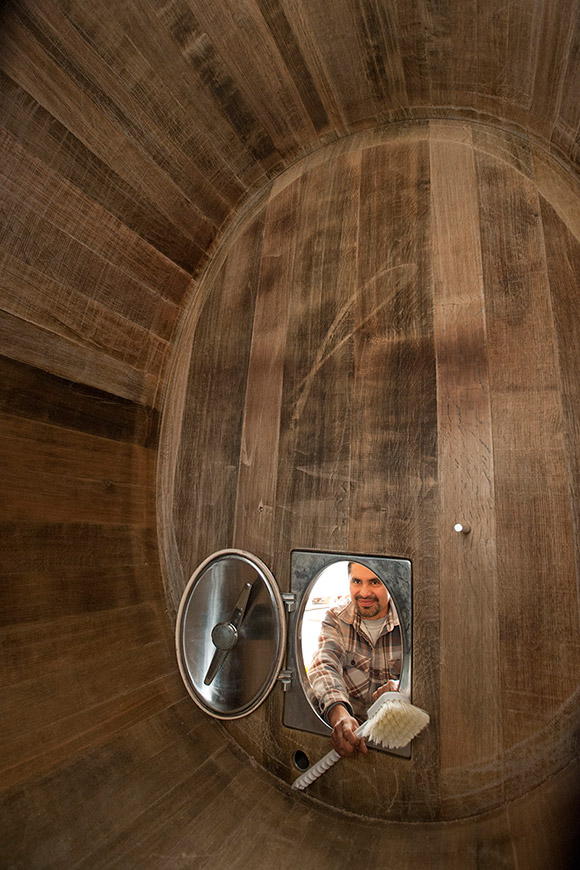 The view from inside a large oak wine oval, Ulises outside with a scrub brush ready to clean it.