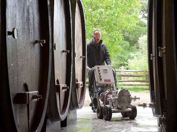Alfredo moving a pump into the cellar with medium sized ovals—about 650 gallons—to rack the wine off its lees.