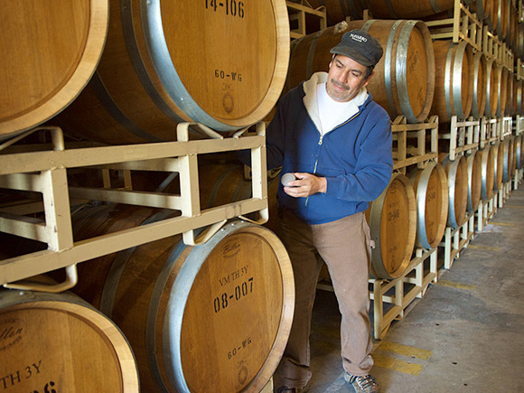 Manuel standing by a stack of French oak barrels.