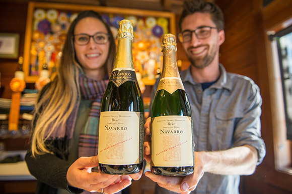 Julia and Tyler, Navarro employees, holding a bottle each of Navarro Brut Sparkling Wine