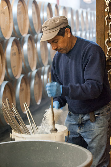 Manuel cleaning spouts to the bottle-filler making sure equipment is sterile for juice bottling.